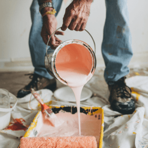 Man pours orange paint into a roller paint pan in a demonstration on how to protect a new paint job.